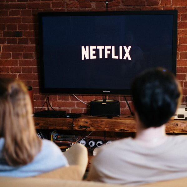 man and woman sitting on a couch in front of a television